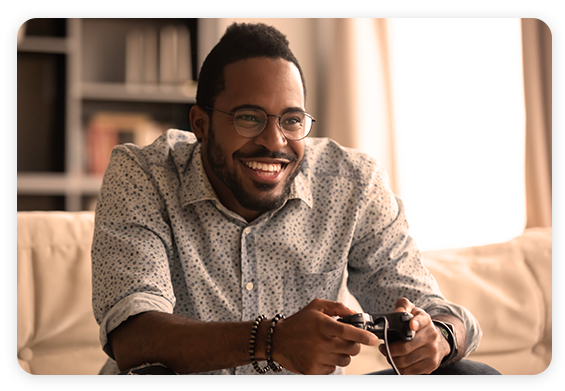 Tealium CDP for Gaming - African American man playing video game and smiling Tealium CDP for Gaming - African American man playing video game and smiling